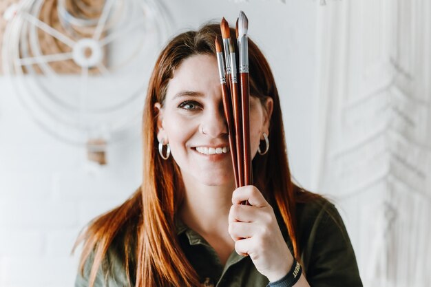 Artist european woman holding brushes