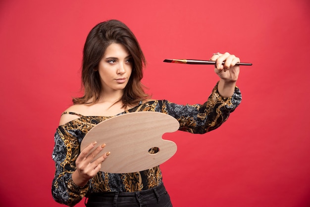 Artist girl taking color from her palette with brush. 