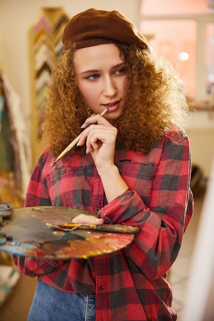 Free photo artist holds a brush and is thinking about during her work