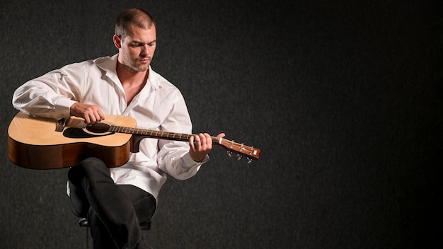 Бесплатное фото Художник в белой рубашке играет на гитаре с копией пространства