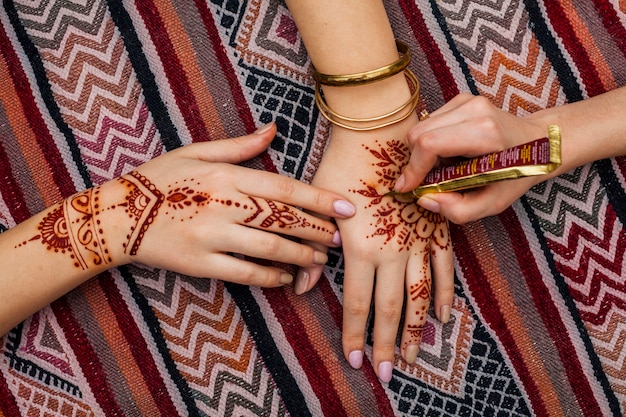 Artist making mehndi on womans hand on bright table