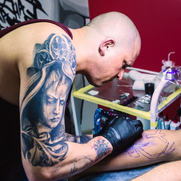 Foto gratuita artista che fa il tatuaggio in studio colorato