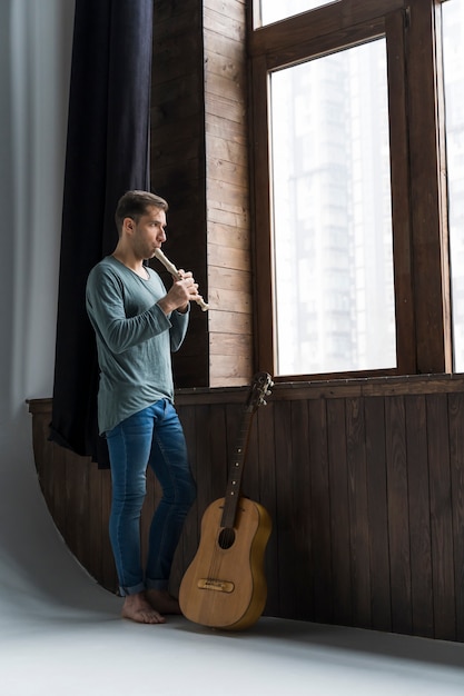 Artist man indoors playing the flute