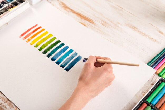 Художник рисует красочные полосы кистью на белой бумаге