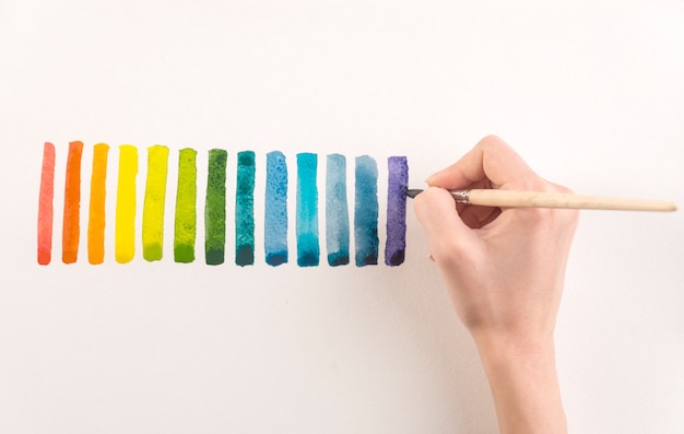 Artist painting colorful stripes with brush on white paper