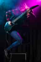 Foto gratuita artista che suona la chitarra e salta di lato