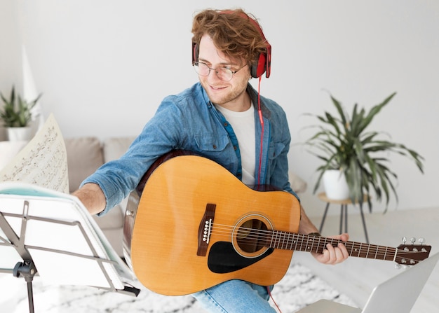 Free photo artist playing guitar and wearing headphones