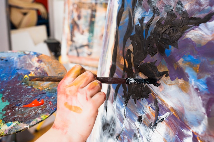 Free Photo artist's hand painting with black brushstroke on canvas