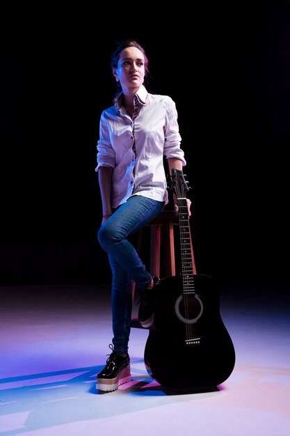 Artist on stage sitting on a chair and holding the guitar