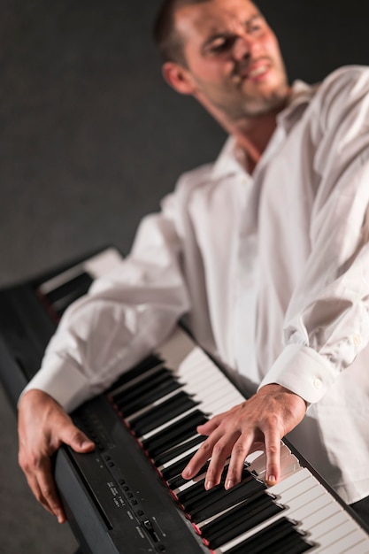 Artist in white shirt holding and playing digital piano