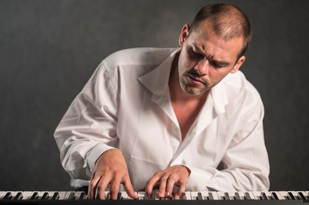 Artist in white shirt looking at keyboards