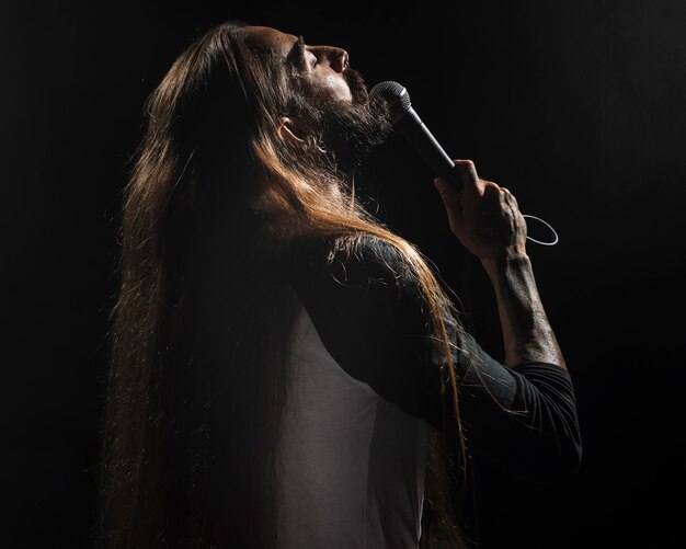 Artist with long hair holding a microphone on stage