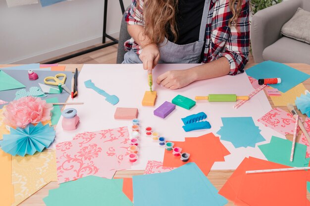artist woman hand cutting colorful clay using clay cutter on table