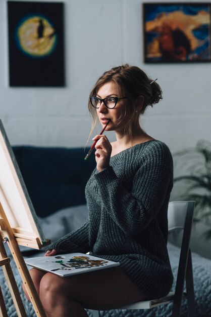 Artistic woman looking at canvas