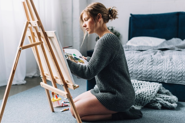 Free photo artistic woman painting in bedroom