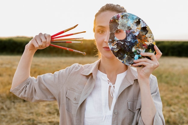 Free photo artistic young woman holding paint brushes