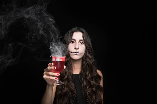 Foto gratuita donna cenere che tiene vetro con liquido rosso che brucia