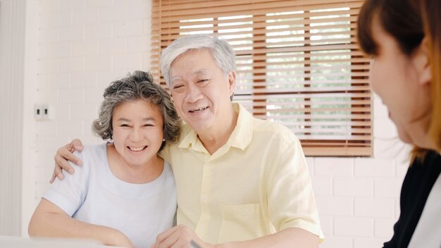 아시아 스마트 여성 에이전트는 문서, 태블릿 및 랩톱으로 노인 커플을위한 건강 보험을 제공합니다.