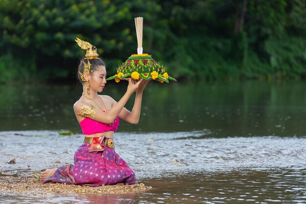 Азиатская женщина в тайском традиционном владении kratong. Фестиваль лой кратонг