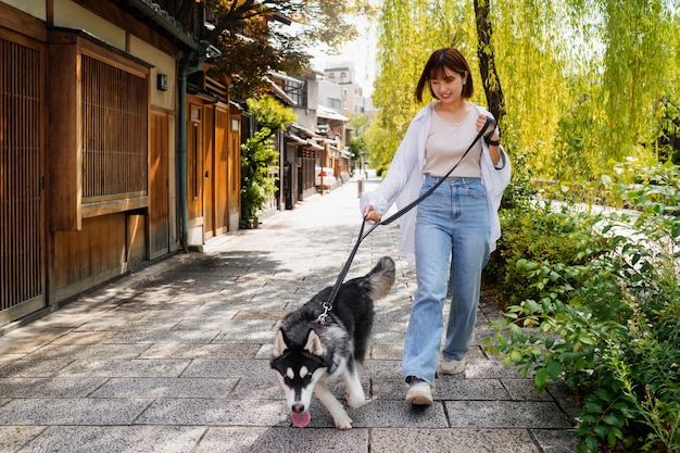 Foto gratuita donna asiatica che porta a spasso il suo cane husky all'aperto