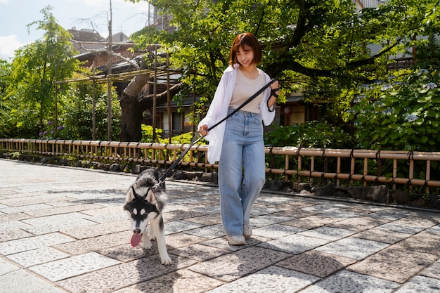 야외에서 허스키 개를 산책시키는 아시아 여성
