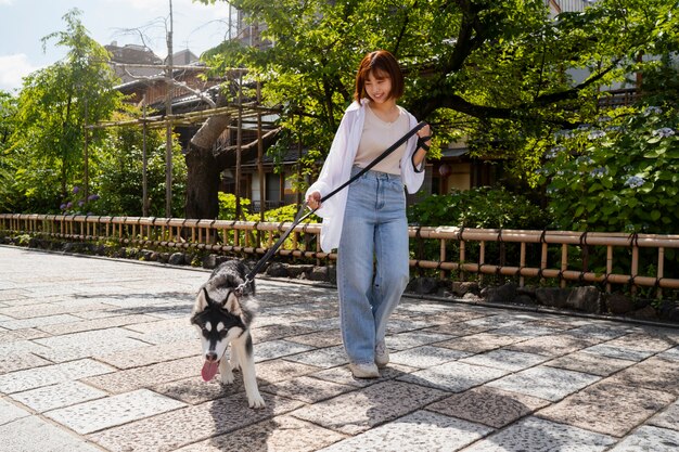 Азиатская женщина выгуливает свою хаски-собаку на улице