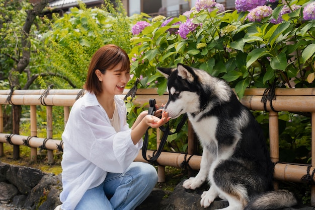 야외에서 허스키 개를 산책시키는 아시아 여성