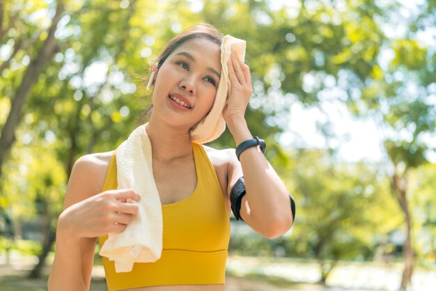 公園の庭でのランニングセッションの後、アジアのアクティブな女性ランナーのトレーニングが腰をかがめて息を呑む朝の運動ライフスタイルで走った後に休憩するスポーツの女性女性