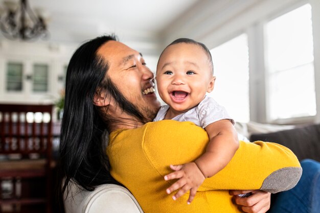 Asian American father hugging his little son