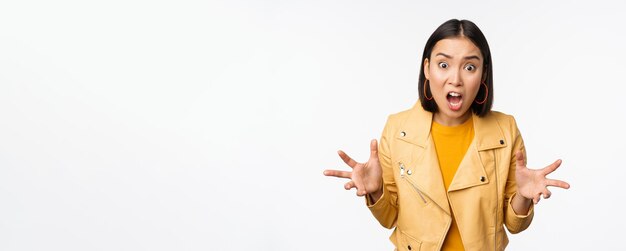 Asian angry woman arguing shaking hands angry and screaming shouting with frustrated face standing over white background