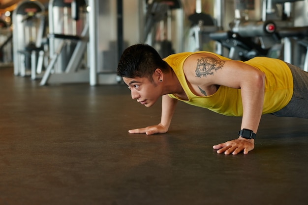 Азиатский спортсмен делает отжимания в тренажерном зале