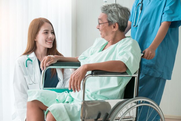 Азиатская привлекательная женщина-врач и медсестра заботятся о пожилом пожилом пациенте-инвалиде на инвалидной коляске в больничном здравоохранении и поддерживают концепцию идей