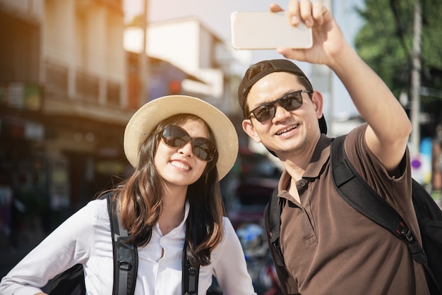 Free photo asian backpack couple tourist holding city map crossing the road - travel people vacation lifestyle concept