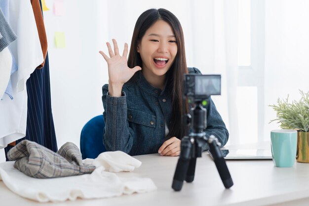 아시아의 아름다운 아시아 블로거 또는 블로거는 옷감 드레스 온라인 비즈니스 상점 온라인 아이디어 개념을 제시합니다.