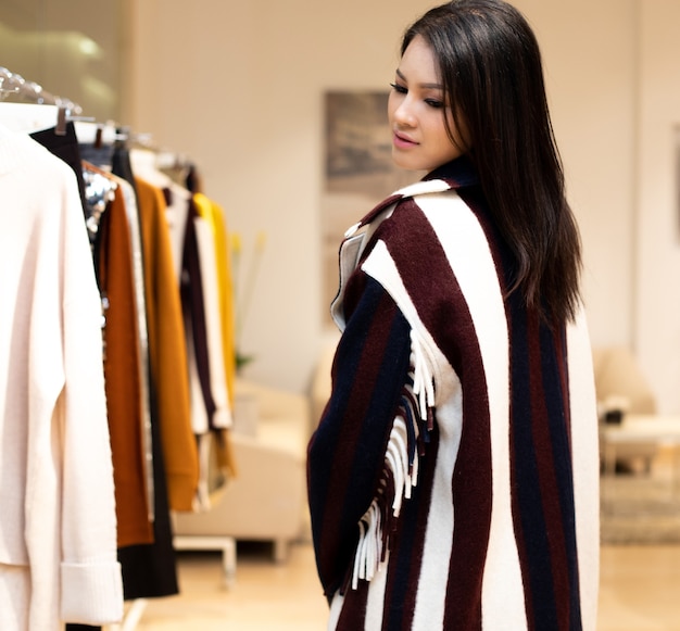 Asian beautiful woman in black white dress select new collection on ready to wear clothes rack in retail fashion store which just open brand news for winter autumn as casual style