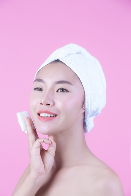 Asian beautiful woman wiping the face on a pink background, Cosmetology and Spa .