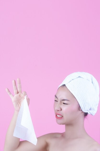 Asian beautiful woman wiping the face on a pink background, Cosmetology and Spa .