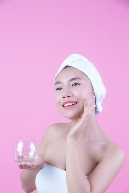 Азиатская красивая женщина, вытирая лицо на розовом фоне, косметология и спа.