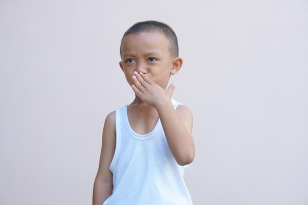 Free photo asian boy covering nose with hands to prevent bad smell