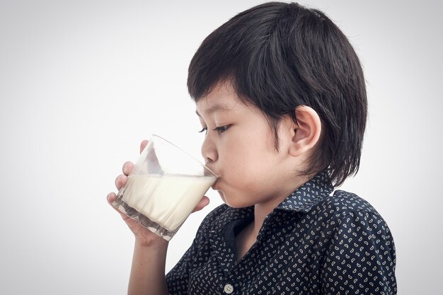 アジアの少年はミルクのガラスを飲んでいます