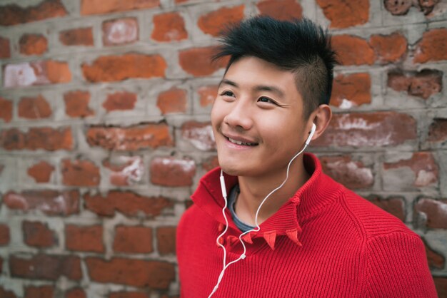Asian boy listening to music with earphones.