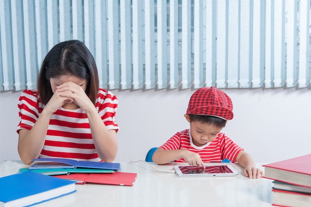 Asian boy playing tablet and his mother frustrated.