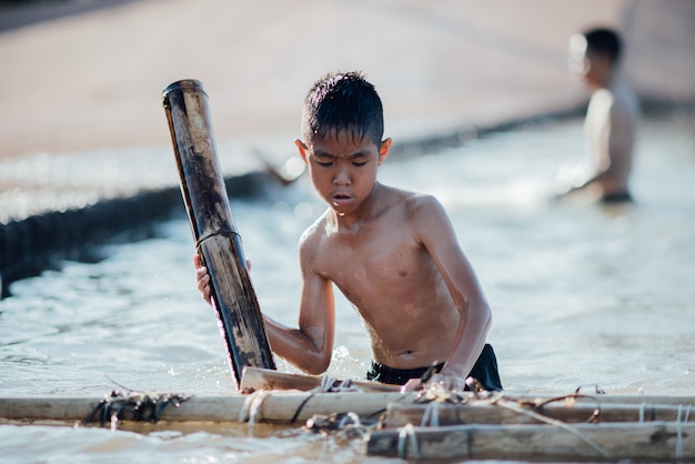 Asian boy playing wooden boat in the river