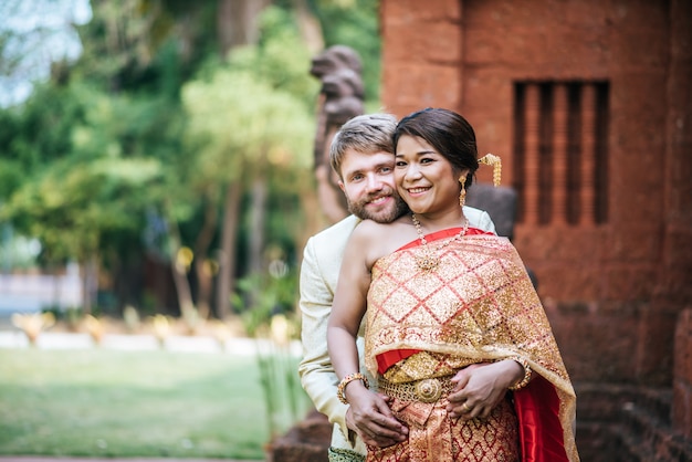 Азиатская невеста и кавказский жених проводят романтическое время в тайском платье