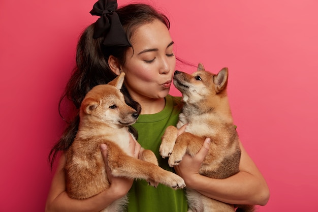 Asian brunette woman kisses dogs with love, pets shiba inu pets, being responsible owner of animals, spend leisure at home