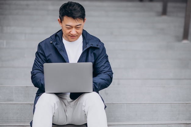 Free photo asian business man sitting on stairs and working on computer