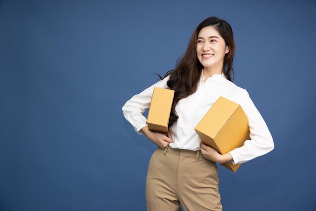 Азиатская деловая женщина, держащая пакет посылки, изолирована на темно-синем фоне