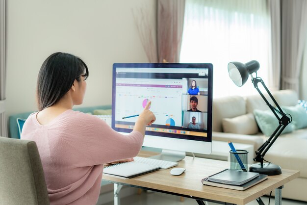 Asian business woman talking to her colleagues about plan in video conference with business team using computer for an online meeting in video call.