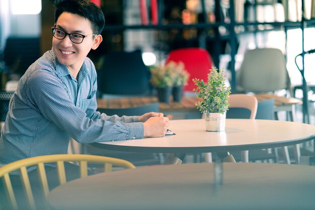 아시아 사업가 신생 기업 기업가는 새로운 상점 상점 배경 비즈니스 아이디어 개념에 행복을 안고 미소를 지으며 앉아 있습니다.