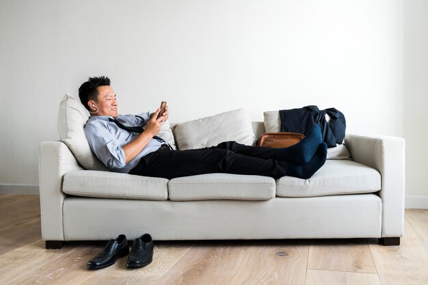 Азиатский бизнесмен, принимая перерыв, лежа на диване